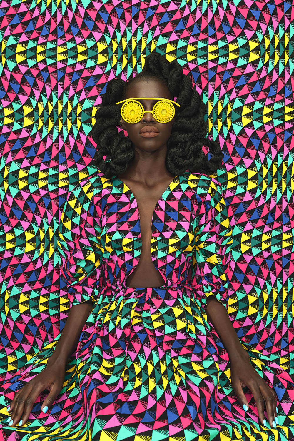 ritratto di donna africana con tessuto ankara a triangoli rosa, fuchsia, giallo, blu, verdi e neri